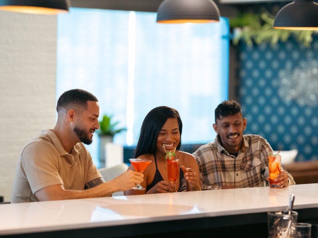 Three guests raising cocktails together at the bar