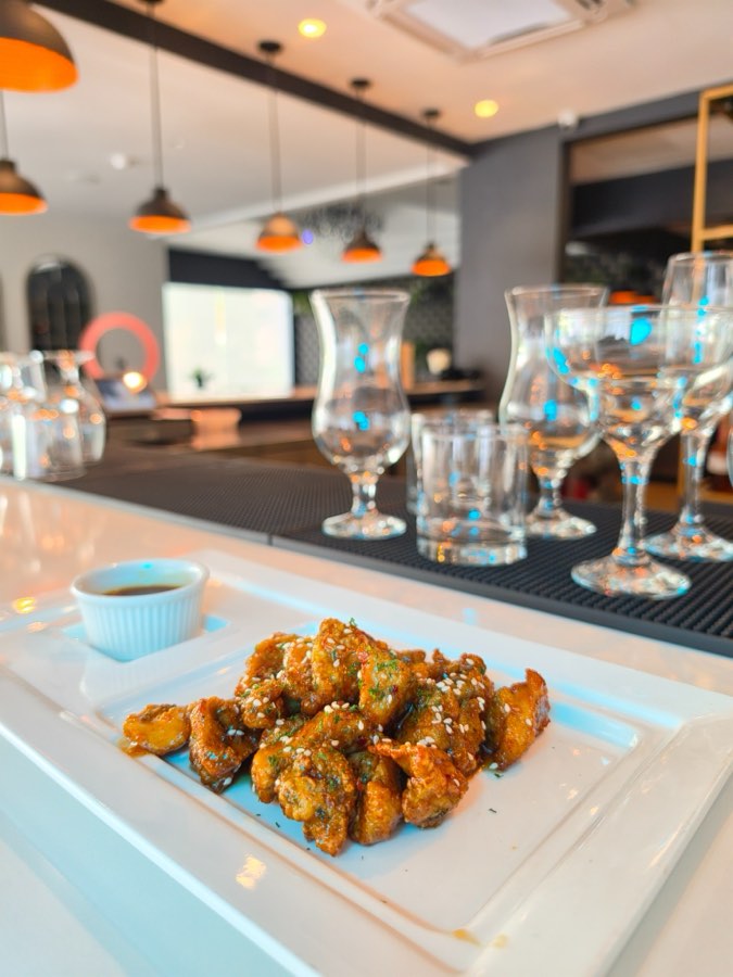 Glazed firecracker chicken bites with sesame on a platter at the bar